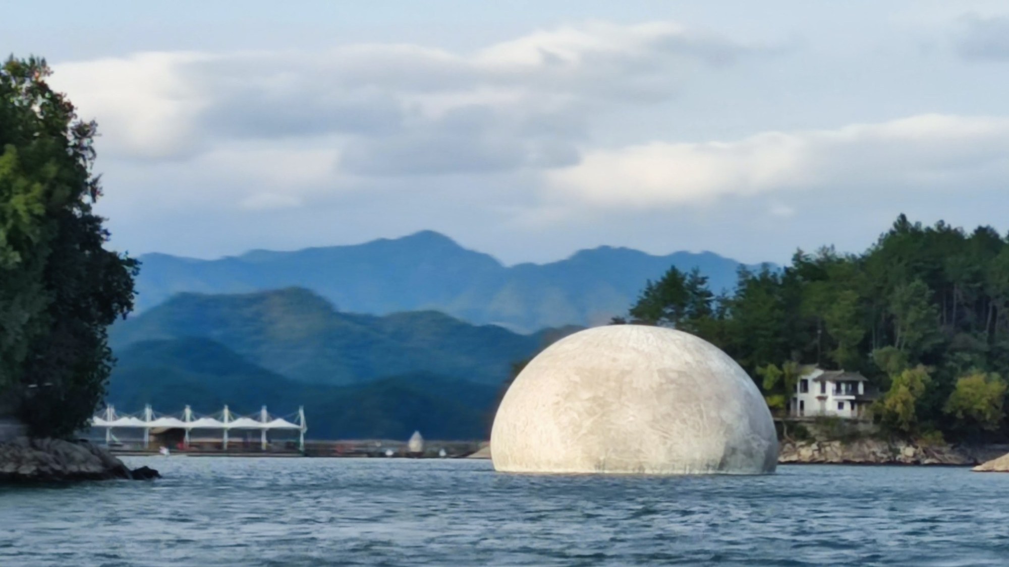 Weiße Kugel im Wasser vor den Bergen